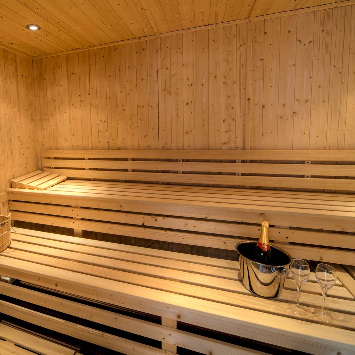 Wooden sauna interior with champagne bottle in ice bucket and two glasses