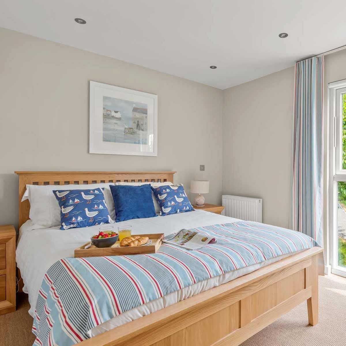 Bedroom with wooden bed, striped bedding, and a breakfast tray
