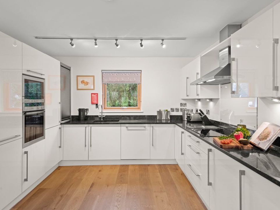 Modern white kitchen with black countertops and wooden floor