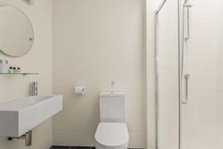 Modern white bathroom with toilet, sink, glass shower, and wall mirror