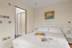Cozy bedroom with white bedding, bedside tables, a tray with breakfast, and an ensuite bathroom.