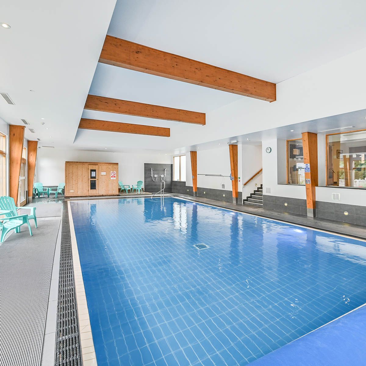 Indoor swimming pool with wooden beams and seating area