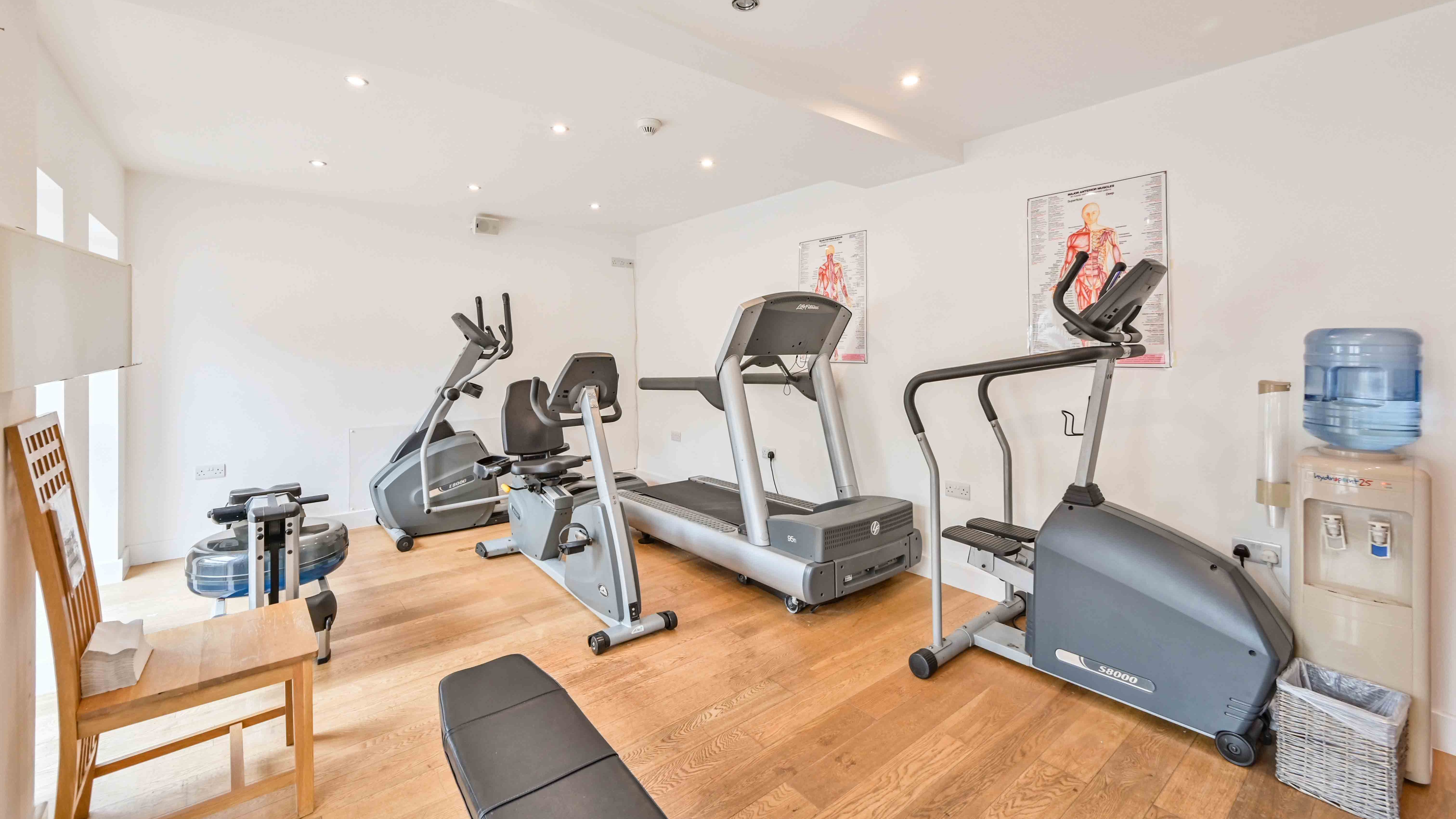 Small gym room with exercise machines and a water dispenser