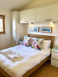 Bright and cozy bedroom with a double bed, colorful pillows, and modern cabinets above.