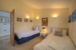Cozy twin bedroom with nautical-themed decor, featuring two single beds, soft lighting, and sea-inspired artwork.