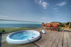 Hot tub and outdoor dining area on a deck with ocean view