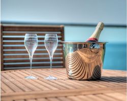 Two champagne glasses and a bottle of champagne in an ice bucket on a wooden table