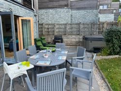 Outdoor patio area with table, chairs, high chair, and hot tub