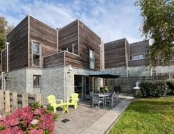 Modern house with wooden and stone exterior, outdoor patio furniture, and garden