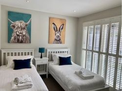 Twin bedroom with white beds, animal artwork on the wall, and folded towels on the beds