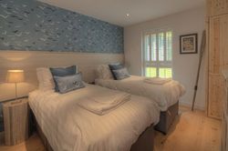 Cozy bedroom with two single beds, blue accent wall with bird patterns, and natural wood furnishings