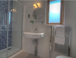 Modern bathroom with glass shower, sink, mirror, window, and heated towel rail.