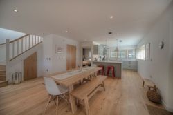 Modern open-plan kitchen and dining area with wooden floors and minimalist decor