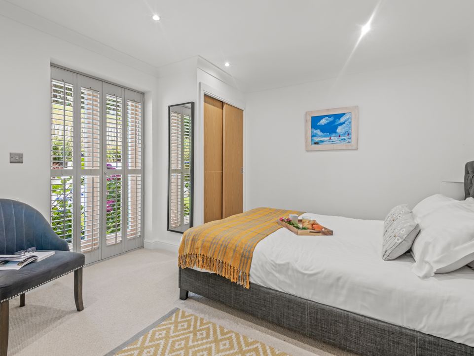 Modern bright bedroom with large windows, a double bed, and a chair.