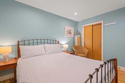 Cozy bedroom with a double bed, wicker chair, wooden nightstands, lamps, and teal walls.