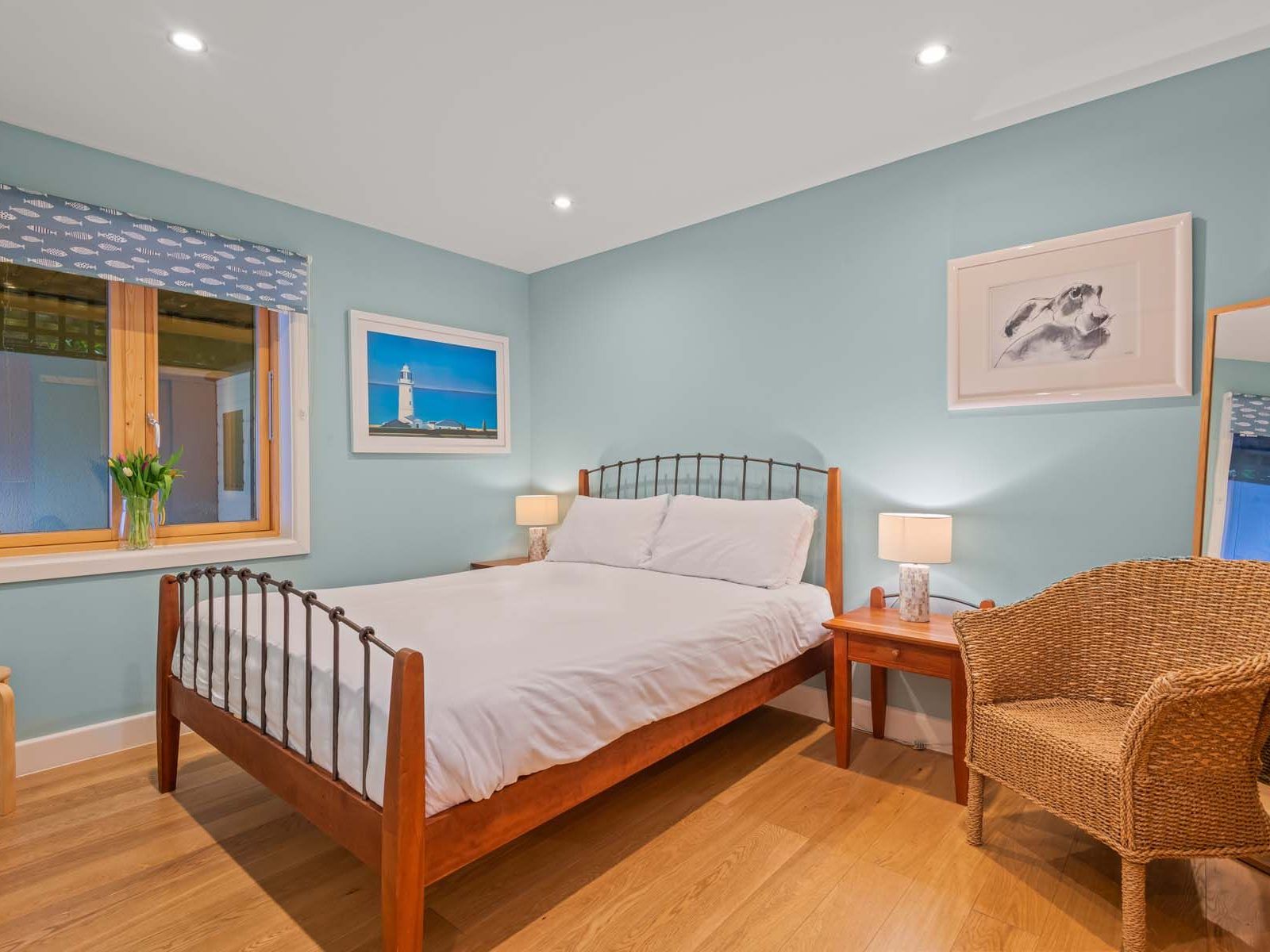 Cozy bedroom with a wooden bed, wicker chair, and sea-themed decor