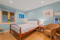 Cozy bedroom with a wooden bed, wicker chair, and sea-themed decor