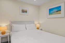 Modern bedroom with white bed, bedside tables, and framed pictures on the wall.