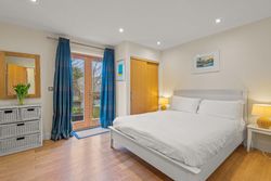 Bright bedroom with white bed, wooden floor, and blue curtains