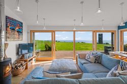 Modern living room with large glass doors overlooking green lawn and ocean view