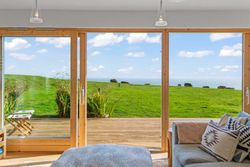 Room with large glass doors overlooking a grassy field and sea view