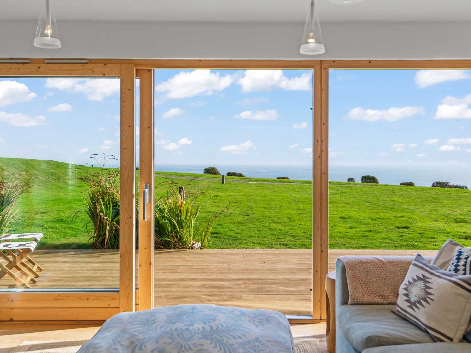 Room with large glass doors overlooking a grassy field and sea view