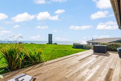 Wooden deck with ocean view and grassy lawn