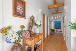 Bright and decorated hallway with wooden beams, artwork, flowers, and rustic furniture.