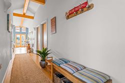 Bright hallway with wooden ceiling beams, cushioned bench, and a 'No Nude Bathing' sign on the wall.
