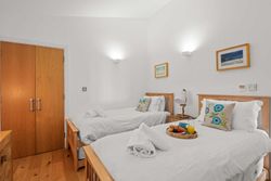 Bright twin bedroom with wooden beds, white linens, decorative pillows, and a breakfast tray.