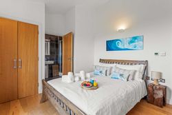 Modern bedroom with wooden bed, white linens, and a tray of breakfast items on the bed