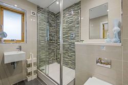 Modern bathroom with glass shower enclosure, mosaic tile wall, and contemporary fixtures.