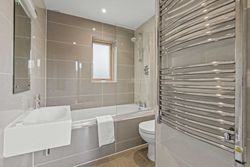 Modern bathroom with a bathtub, sink, toilet, and heated towel rail