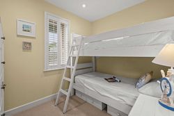 Small bedroom with white bunk beds, a window with shutters, and nautical-themed decor.