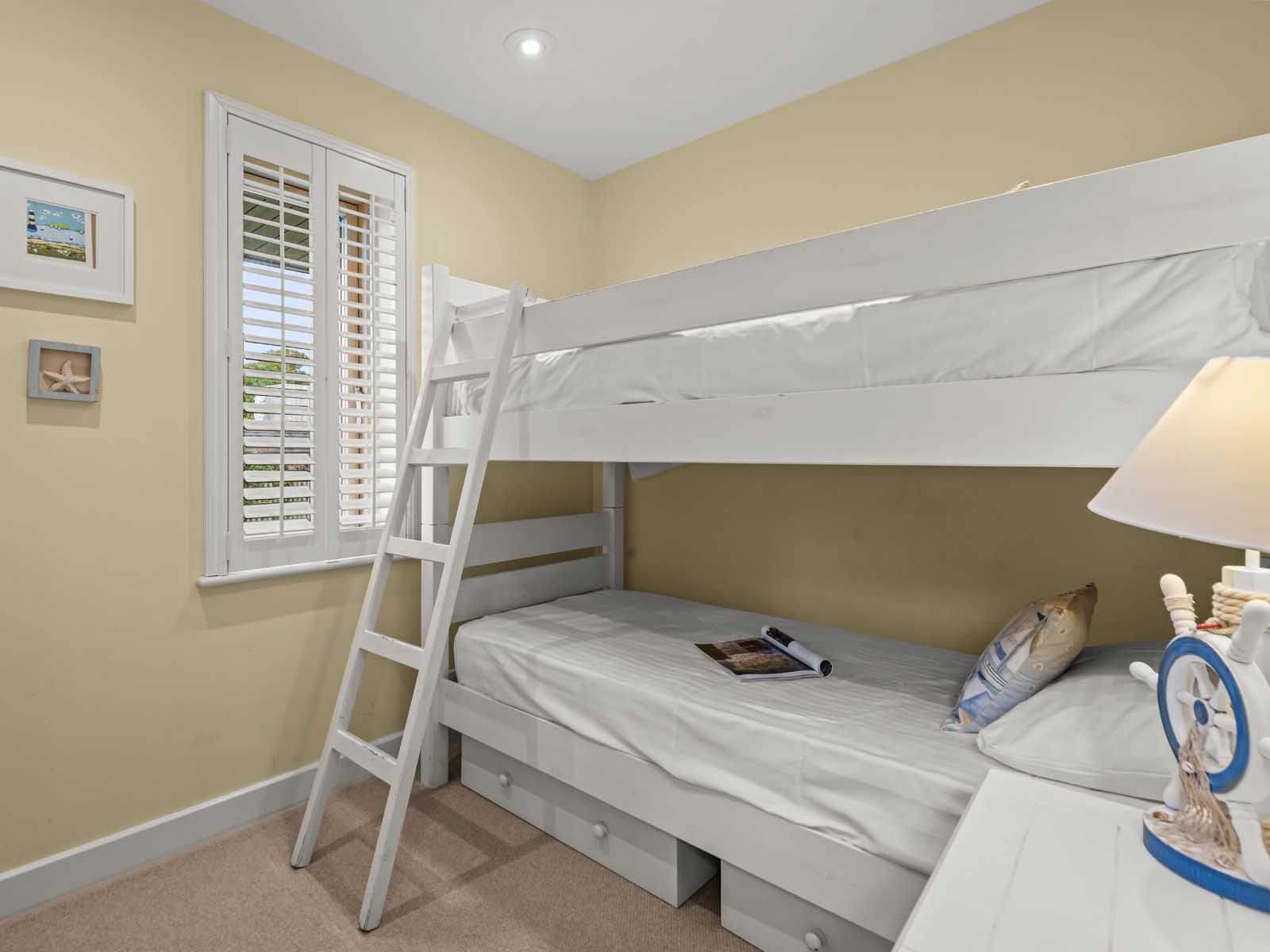 Small bedroom with white bunk beds, a window with shutters, and nautical-themed decor.