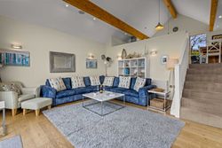 Modern living room with blue corner sofa, decorative pillows, and staircase leading to dining area