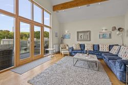 Modern living room with large windows, blue sectional sofa, and light wooden floors