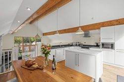 Modern open-plan kitchen with wooden beams, white cabinets, and a dining table set for two.