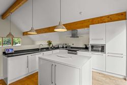Modern kitchen with white cabinets, black countertops, and wooden beams.