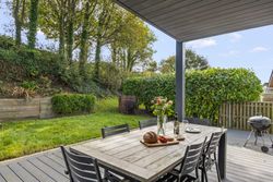 Outdoor patio dining area with table, chairs, flowers, food, and a barbecue grill