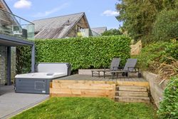 Outdoor deck area with hot tub and lounge chairs surrounded by greenery