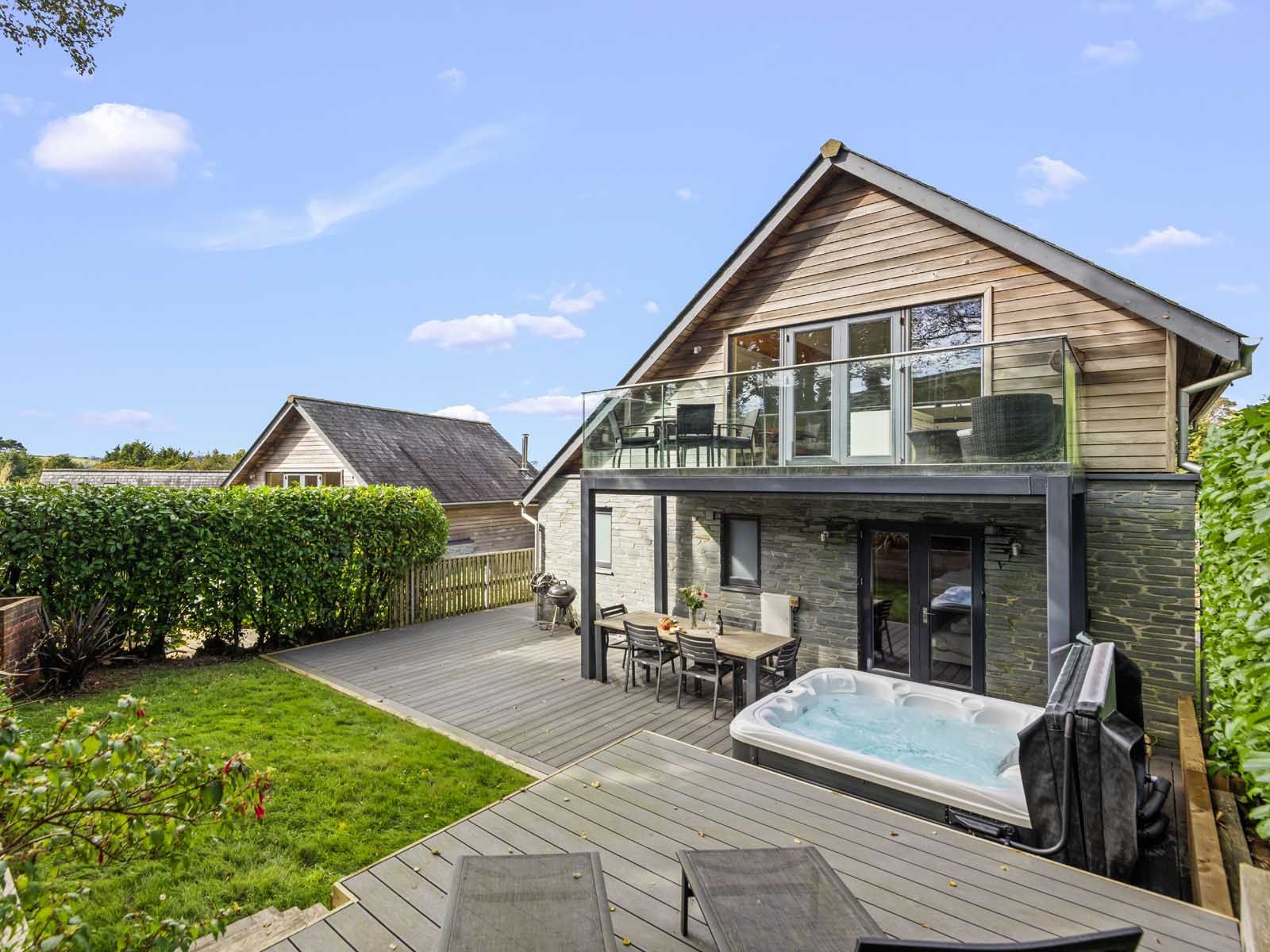 Modern house with outdoor deck, hot tub, and glass balcony