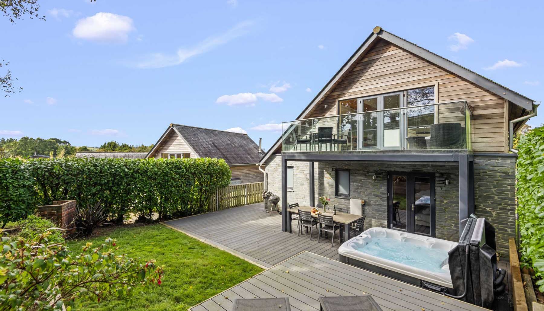 Modern house with outdoor deck, hot tub, and glass balcony