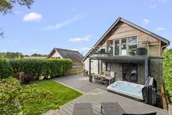 Modern house with outdoor deck, hot tub, and glass balcony