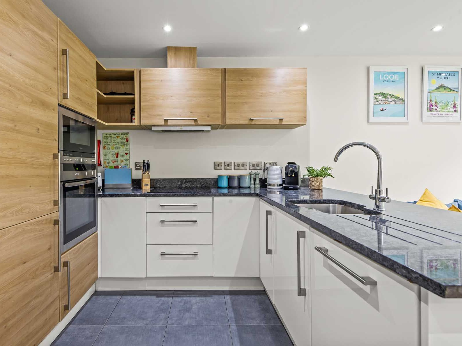 Modern kitchen with wooden and white cabinets, built-in appliances, and granite countertops