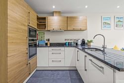 Modern kitchen with wooden and white cabinets, built-in appliances, and granite countertops