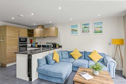 Modern open-plan kitchen and living area with blue sofa and yellow cushions