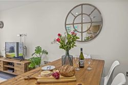Dining table set with wine, bread, cheese, grapes, and flowers in a modern living space