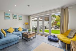 Modern living room with blue sofa, yellow chair, and large glass doors opening to a garden patio.