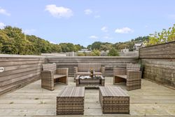 Outdoor rooftop patio with wicker furniture and surrounding wooden fencing